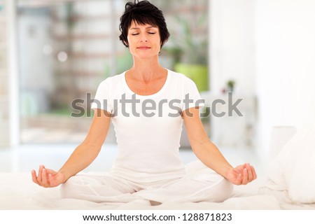 beautiful middle aged woman meditation on bed at home