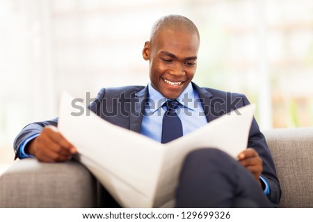 handsome african corporate worker reading newspaper in office