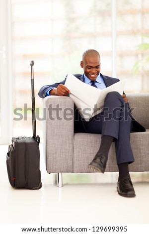 African Businessman Reading Newspaper In Airport Vip Lounge