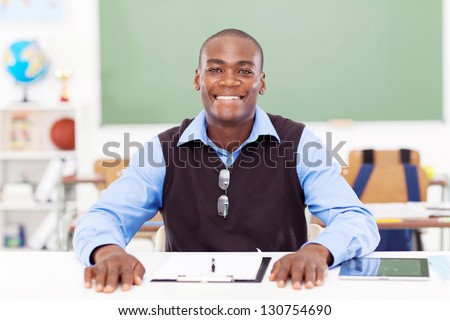 African male primary teacher sitting in classroom alone