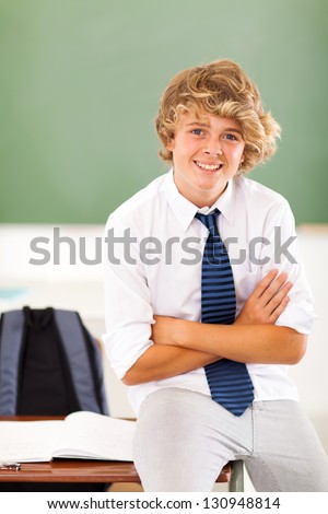 middle school teen student sitting on desk in classroom