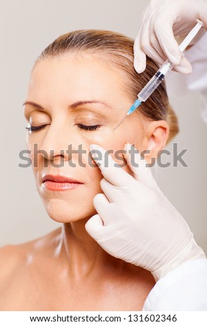 senior woman receiving plastic surgery injection on her face