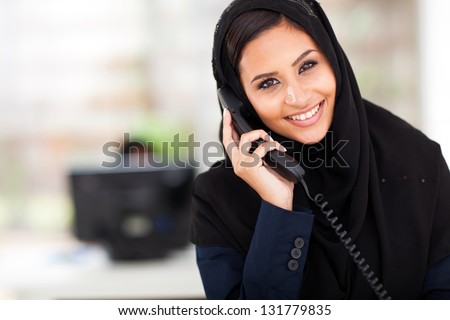 young happy Muslim businesswoman talking on landline phone