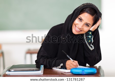happy female middle eastern high school student sitting in classroom
