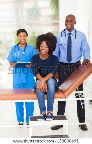 young african woman in doctor\'s office with doctor and nurse