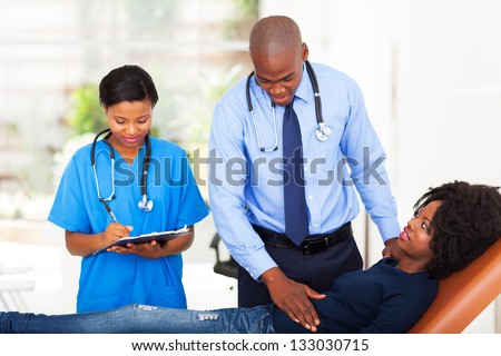 african doctor and nurse examining female patient in office