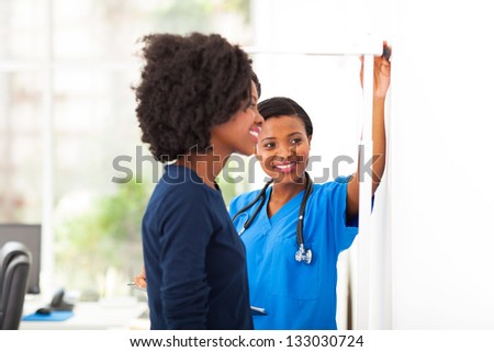 friendly african nurse measuring patient\'s height