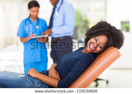 happy african woman lying on doctor\'s examining bed and waiting for medical checkup