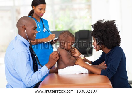 male african doctor examining a baby boy in his office