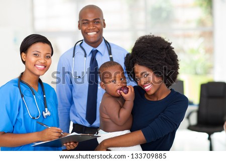 happy afro american mother holding her baby boy after checkup with nurse and doctor
