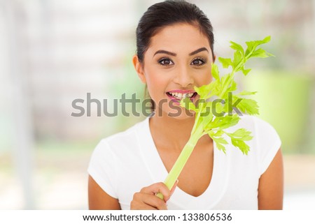 young female vegetarian biting celery\'s leaves