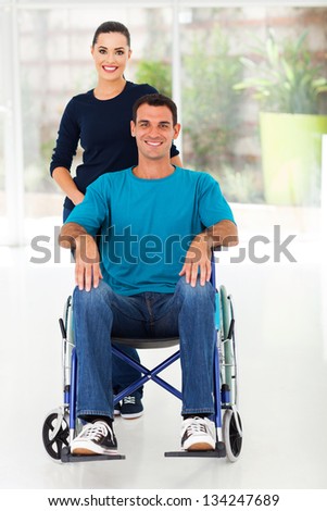 handicapped man sitting on wheelchair with caring wife at home