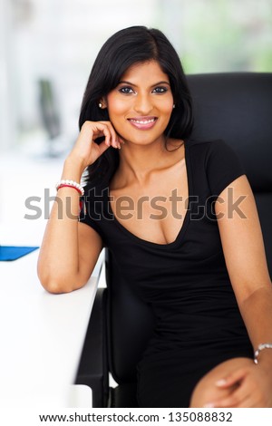 attractive young indian office worker sitting by office desk