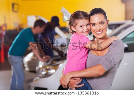 young mother and daughter waiting in garage while father talking to mechanic