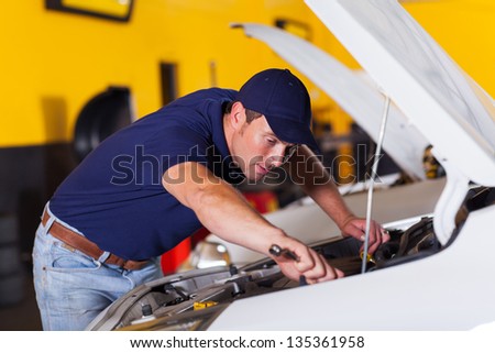 auto mechanic repairing vehicle inside workshop