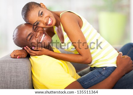 portrait of happy couple on sofa at home flirting