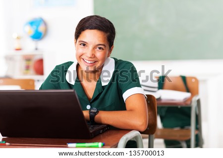 happy female middle school student using laptop in classroom