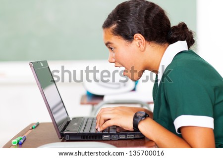 surprised middle school girl looking at her laptop in classroom