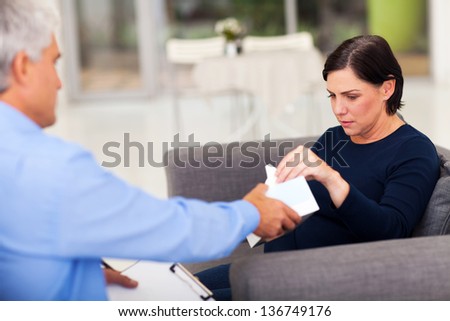 understanding therapist handing tissue to an upset middle aged patient