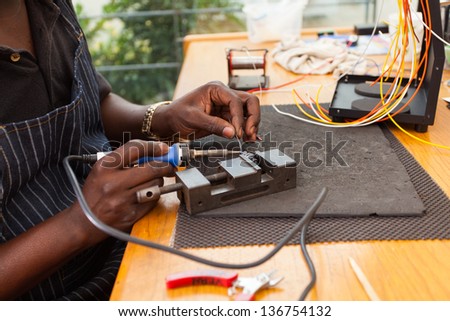 senior african electrician using soldering iron repair a push button