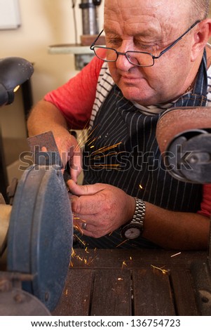 senior repairman using grinding machine in workshop