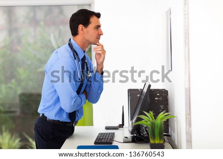 male doctor looking at the medical chart in office