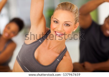 beautiful fit woman stretching in gym with friends