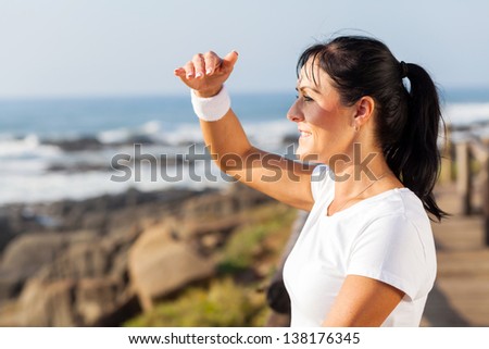 fit mature woman looking into distance at beach in the morning