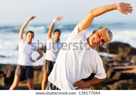 Happy Mid Age Man Exercising At The Beach With His Family