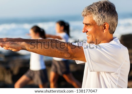side view of healthy middle aged man exercising with family at the beach