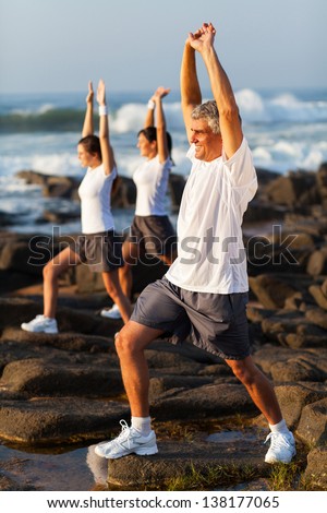 middle aged man exercising with his family at the beach