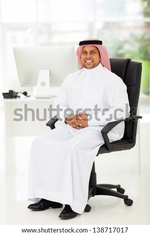 smiling middle eastern businessman sitting in modern office