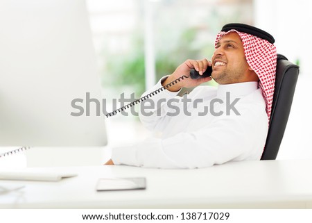 cheerful arabian corporate worker talking on the landline phone