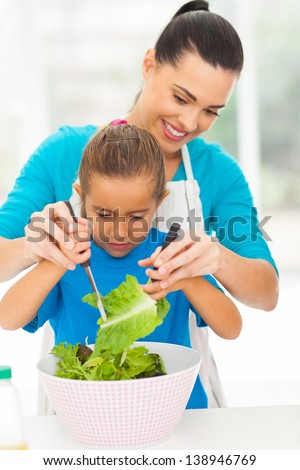 Loving Mother Teaching Little Daughter Mixing Salad At Home