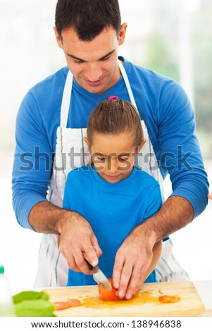 loving father teaching little daughter cooking in kitchen
