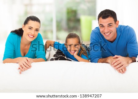 happy young family lying on bed with their pet dog at home