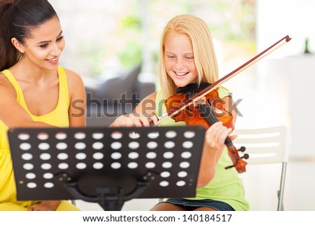 cheerful pre teen girl enjoying her violin lesson with music teacher at home