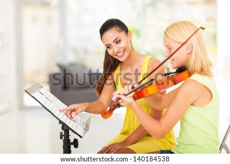 preteen girl play violin under music teacher\'s instructions
