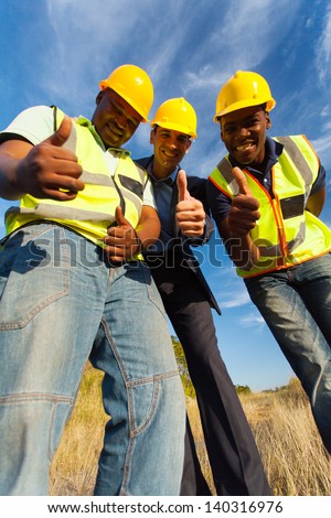 happy construction workers giving thumbs up outdoors