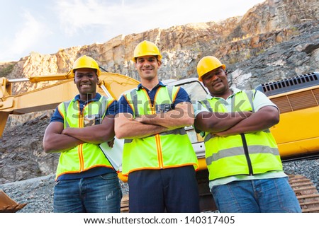 group of quarry workers standing next to excavator with arms crossed group of quarry workers standing next to excavator with arms crossed