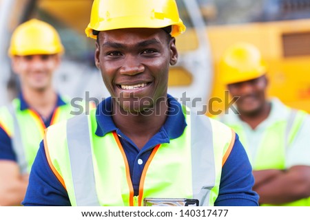 happy african american construction worker in front of colleagues