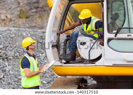 cheerful construction foreman talking to excavator operator
