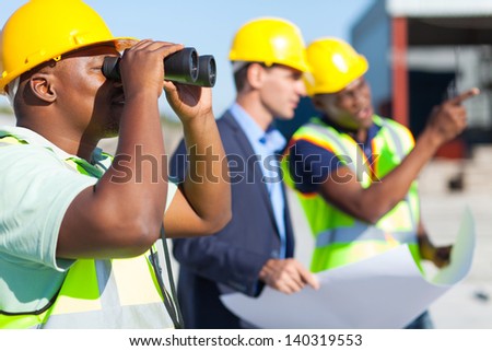 african construction worker using binoculars looking at construction site