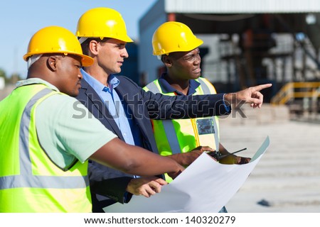 Group Of Architect And Construction Workers On Site With Blue Print