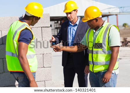 construction workers with their manager checking bricks quality