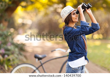 attractive young woman using binoculars bird watching at the park