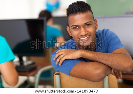 handsome male indian high school student looking back in classroom