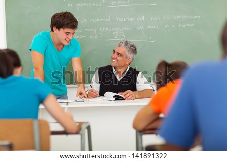 friendly senior high school teacher helping a student with the class work
