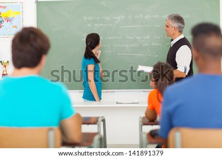 high school girl been called to chalkboard by senior teacher during biology lesson
