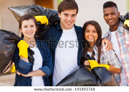 cheerful young volunteers with garbage bag after cleaning the streets